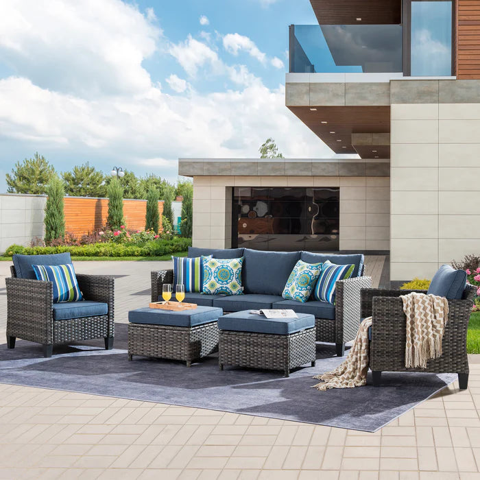 Gray wicker patio furniture set with blue cushions on a patio.